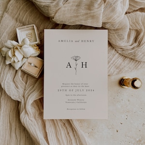K&ouml;nnte beinhalten: Hochzeitseinladung mit beigefarbenem Hintergrund und schwarzem Text. Die Einladung lautet "Amelia und Henry" mit einem floralen Design und den Initialen "AH". Das Datum der Hochzeit ist der 29. Juli 2024, und der Ort ist Avensole Winery in Temecula, Kalifornien.