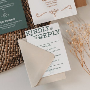 K&ouml;nnte beinhalten: Eine wei&szlig;e RSVP-Karte mit einer gr&uuml;nen und wei&szlig;en &Uuml;berschrift "Kindly Reply". Die Karte hat einen Bereich f&uuml;r Namen und ein Kontrollk&auml;stchen zum Akzeptieren oder Ablehnen der Einladung. Die Karte liegt auf einem beigefarbenen Umschlag.