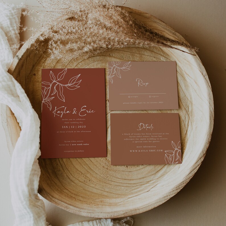 May include: A set of three wedding invitation cards with a brown background and white floral illustrations. The cards include the names "Kayla & Eric", the date "JAN | 12 | 2023", and the text "Rup" and "Details".