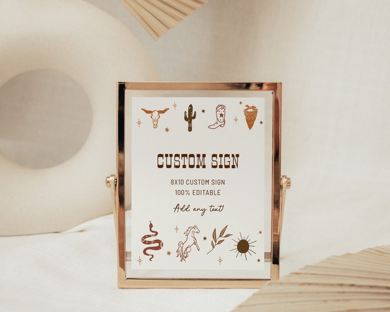 May include: A gold-framed sign with a white background and brown illustrations of a cactus, cowboy boot, skull, and other western-themed imagery. The sign reads "CUSTOM SIGN 8x10 CUSTOM SIGN 100% EDITABLE Add any text".