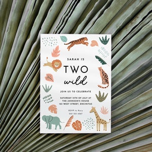 May include: A white invitation card with a jungle theme. The card features a colourful illustration of animals, including a lion, tiger, giraffe, and elephant. The text on the card reads "Sarah is Two Wild" and includes details for a birthday party.