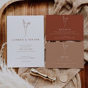 May include: A wedding invitation suite with a minimalist design. The invitation features a simple floral illustration and the text "Lauren & Taylor" in a brown font. The details card is a terracotta color and includes the text "Details" and the website address "www.lauren-taylor.com". The RSVP card is also terracotta and includes the text "RSVP" and a checkbox for "accepts" and "regrets".