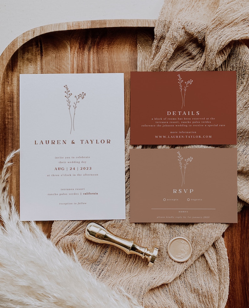 May include: A wedding invitation suite with a minimalist design. The invitation features a simple floral illustration and the text "Lauren & Taylor" in a brown font. The details card is a terracotta color and includes the text "Details" and the website address "www.lauren-taylor.com". The RSVP card is also terracotta and includes the text "RSVP" and a checkbox for "accepts" and "regrets".