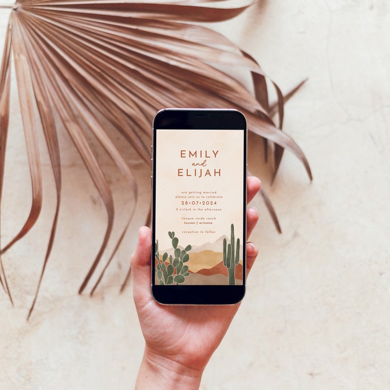 May include: A mobile phone screen displaying a wedding invitation for Emily and Elijah. The invitation features a desert landscape with cacti and mountains in shades of brown, orange, and green. The text reads "Emily and Elijah are getting married, please join us to celebrate, 28-07-2024, 5 o'clock in the afternoon, Tongue Verde Ranch, Tucson, Arizona, reception to follow."