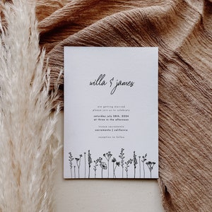K&ouml;nnte beinhalten: Eine wei&szlig;e Hochzeitseinladung mit schwarzem Text, die die Hochzeit von Willa und James ank&uuml;ndigt. Die Einladung enth&auml;lt Datum, Uhrzeit und Ort der Hochzeitszeremonie und des Empfangs. Am unteren Rand der Einladung befindet sich eine Reihe einfacher schwarzer Strichzeichnungen von Wildblumen.