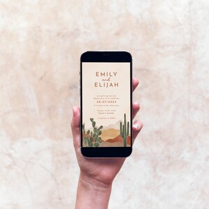May include: A mobile phone screen displaying a wedding invitation with a desert landscape background. The invitation reads "Emily and Elijah are getting married, please join us to celebrate 28-07-2024 at 2 o'clock in the afternoon."