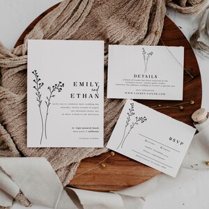 May include: Wedding invitation suite with a minimalist design featuring a floral motif. The invitation card is white with black text and reads "Emily and Ethan". The details card includes the wedding date, location, and website. The RSVP card has a simple design with a floral motif and space for guests to indicate their attendance.