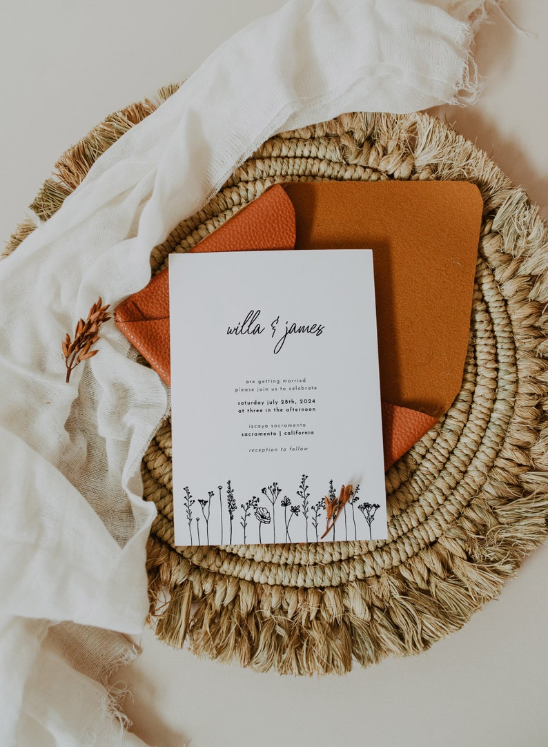 K&ouml;nnte beinhalten: Eine wei&szlig;e Hochzeitseinladungskarte mit schwarzem Text, die die Hochzeit von Willa & James ank&uuml;ndigt. Die Karte zeigt eine einfache Blumenillustration unten und den Text "Samstag, 28. Juli 2024, um 15:00 Uhr Iscaya Sacramento, Sacramento, Kalifornien Empfang folgt."