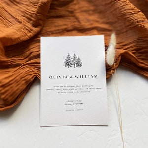 May include: A minimalist wedding invitation with a simple illustration of three pine trees. The invitation reads "Olivia & William" and includes the wedding date, time, and location: "Saturday, twenty fifth of July two thousand twenty three at three o'clock in the afternoon. Silverpick Lodge, Durango, Colorado. Reception to follow."