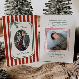 Op de afbeelding: Twee kerstkaarten met familiefoto's. Eén kaart heeft rood-witte strepen met de tekst "The More The Merrier". De andere kaart heeft een foto van een baby en de tekst "We are thrilled to share with you our most precious gift! Wishing you and yours a Merry Christmas and happy New Year."