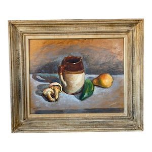 May include: An oil painting in a gold-toned frame depicts a still life. A brown and white pitcher with a handle sits next to a green pepper, a yellow pear, and two mushrooms. The background is a muted brown and gray.