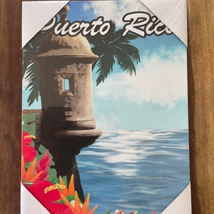 May include: A colourful canvas print featuring a stone building with a palm tree and the words "Puerto Rico" in white text. The building is situated on a cliff overlooking a blue ocean with white waves. The bottom of the print features tropical flowers in shades of red, orange, and yellow.
