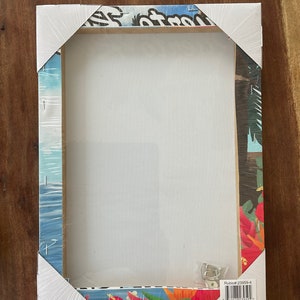 May include: A white canvas print with a tropical design. The print features a blue sky, palm trees, and red flowers. The print is wrapped around a wooden frame and has a hanging hook on the back. The print is packaged in a clear plastic bag with a label that says "Rubioff #23959-4" and "Made in China".