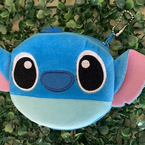 May include: Blue and pink plush Stitch character coin purse with a zipper closure and a metal chain.