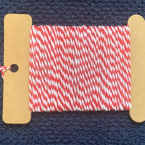May include: Red and white baker's twine wound around two cardboard spools.