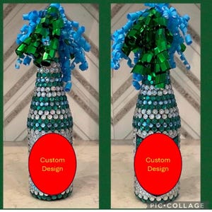 May include: Two champagne bottles decorated with green and blue rhinestones and a green and blue bow. The bottles have a red circle with the text "Custom Design" on them.