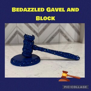 May include: A dazzling blue gavel and block set. The gavel and block are adorned with sparkling blue rhinestones. The text "BEDAZZLED GAVEL AND BLOCK" is in yellow letters at the top. A small gavel illustration is in the bottom right corner.