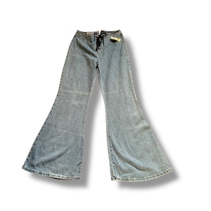 May include: Light blue denim bell-bottom jeans. The jeans have a high waist and a drawstring closure. The legs flare out dramatically from the knee to the hem. A small tag is attached to the front.