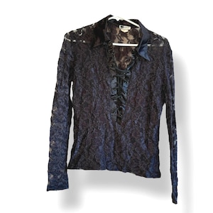 May include: Black lace long-sleeve top with a collared neckline and a satin-like trim. The top features a lace-up detail down the front and is hanging on a white hanger.