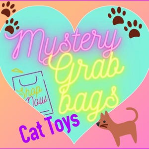 May include: A pink heart-shaped graphic with the text "Mystery Grab Bags Cat Toys" in yellow and pink lettering. The graphic also includes a brown paw print and a cartoon cat.
