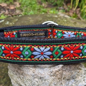 Könnte beinhalten: Schwarzes Hundehalsband mit einem bunten Stickmuster mit roten, weißen, grünen und gelben Blumen. Das Halsband ist mit "Deron-Collars" beschriftet.