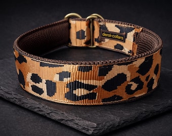 May include: A brown and black leopard print dog collar featuring a woven nylon strap, dark brown interior lining, and two brass-toned metal D-rings. A small rectangular fabric label with the text deroi-collars is stitched onto the outer band.