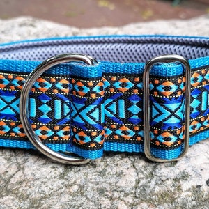 Op de afbeelding: Een blauwe en oranje gepatroneerde hondenriem met een zilveren D-ring en gesp. De riem is gemaakt van een dik, duurzaam materiaal en heeft een gevoerde voering voor comfort.