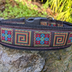 Puede incluir: Un collar de perro negro con un patrón geométrico colorido. El patrón presenta cuadrados con una mezcla de colores rojo, azul, verde y naranja.