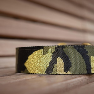 Op de afbeelding: Een zwarte, groene en gouden camouflage hondenriem.