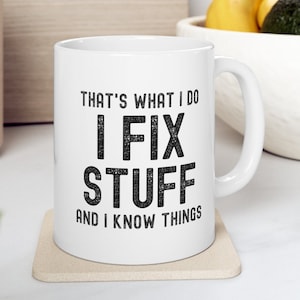 May include: White ceramic coffee mug with a black graphic that reads "That's what I do I fix stuff and I know things".