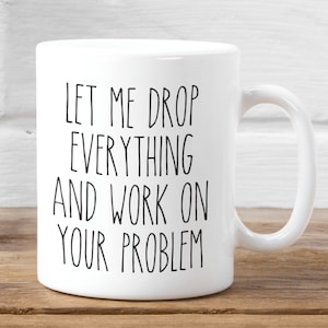 May include: White ceramic coffee mug with black text that reads "Let me drop everything and work on your problem".
