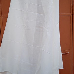 May include: A white sheer fabric scarf hanging on a hanger. The scarf is folded in half and has a smooth texture.