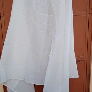 May include: A white sheer scarf, folded and draped over a brown door.