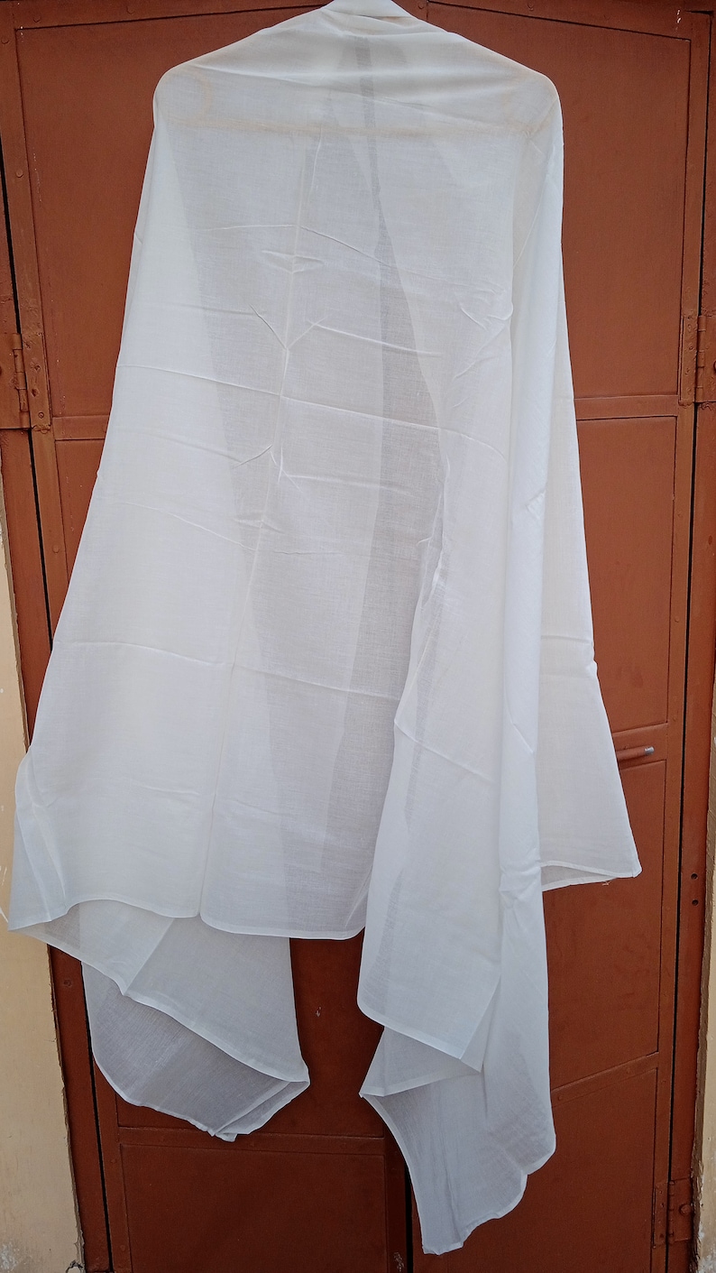 May include: A white sheer fabric scarf hanging on a brown door. The scarf is folded in half and has a smooth texture.