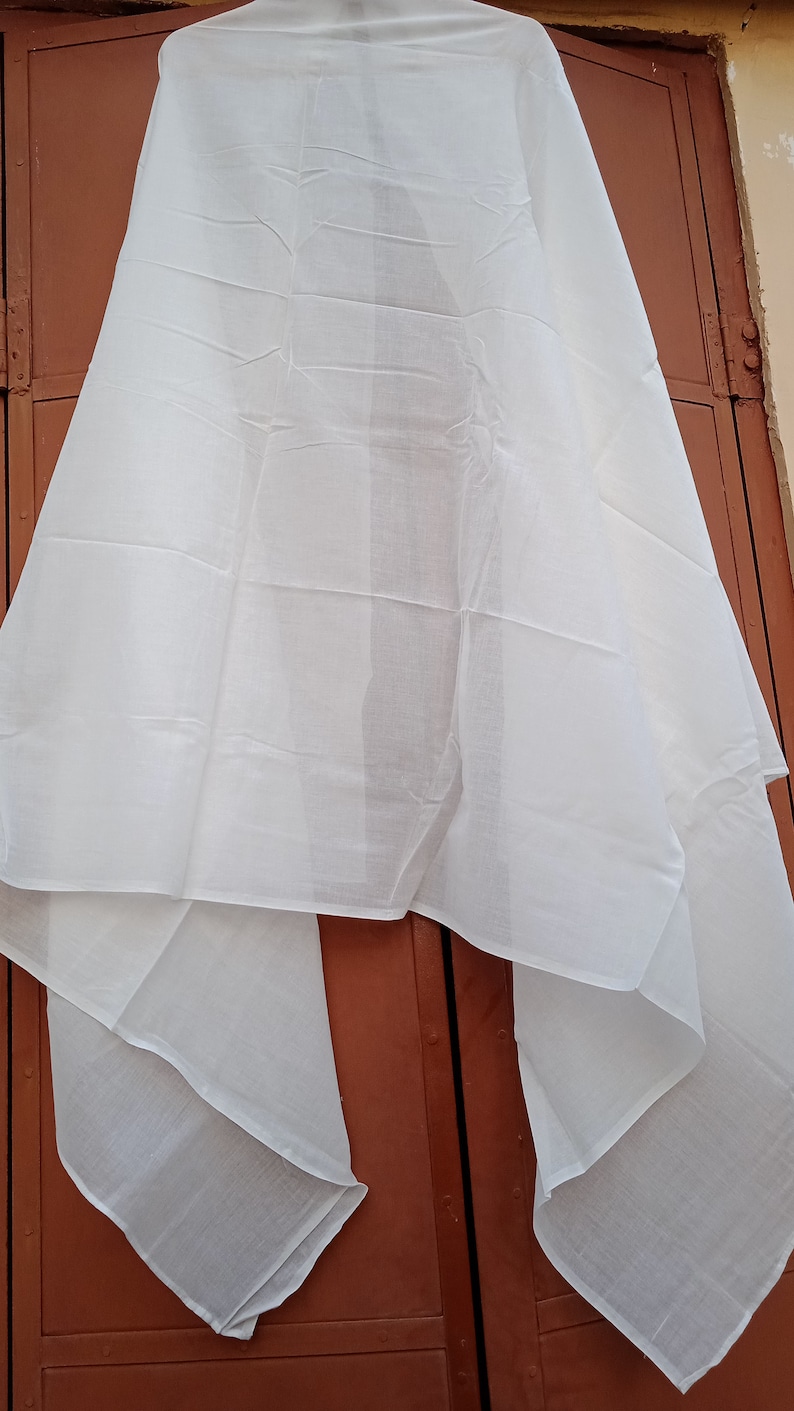 May include: A white sheer fabric scarf, folded and draped over a brown door.