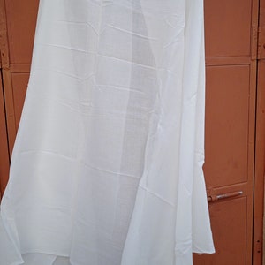 May include: A white sheer scarf hanging on a hanger against a brown wooden door.