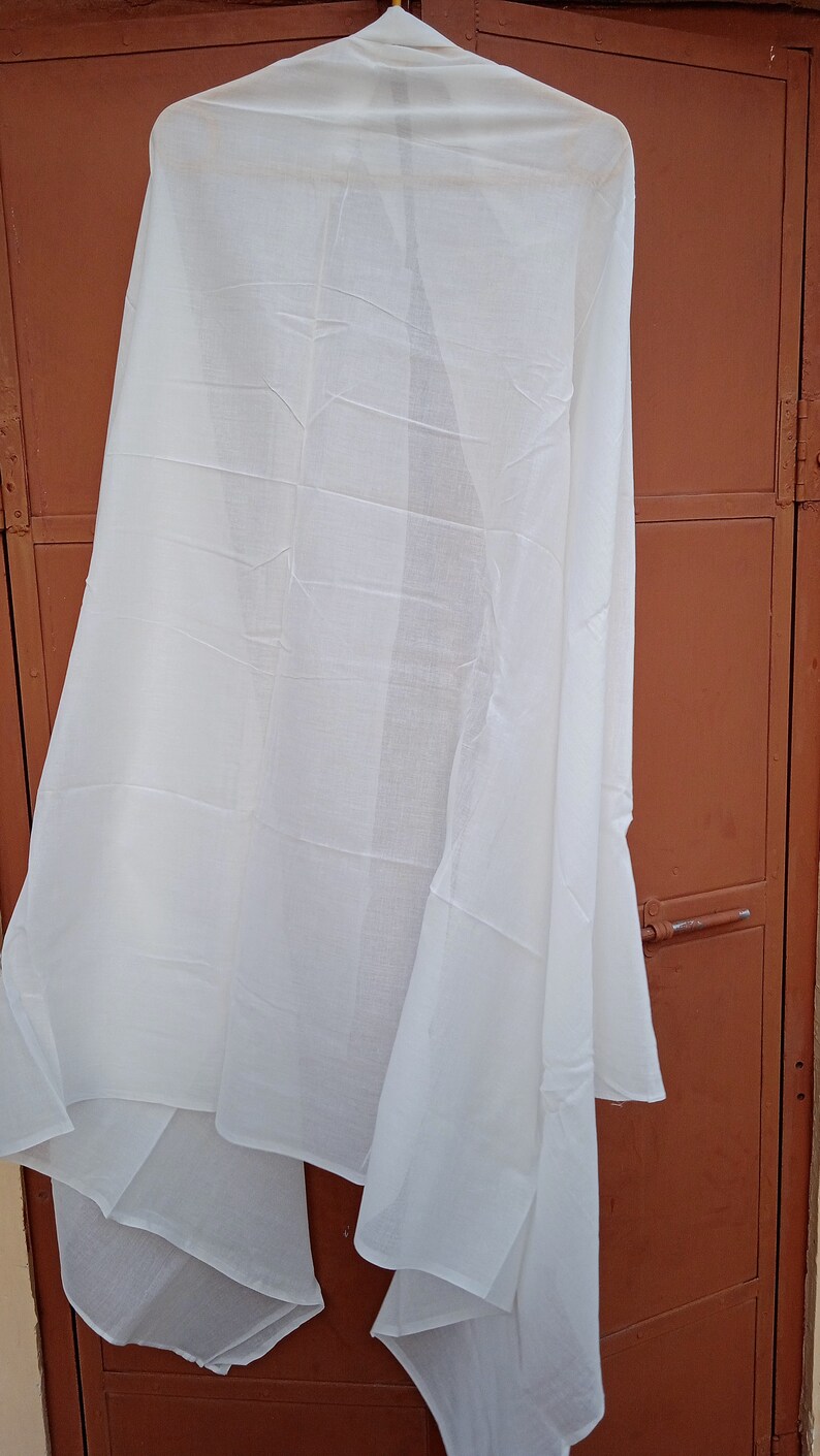 May include: A white sheer scarf hanging on a hanger against a brown wooden door.