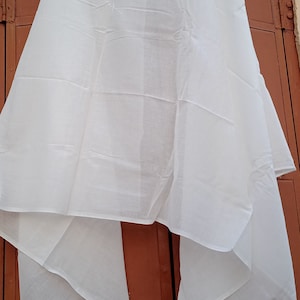 May include: A white cotton scarf draped over a brown door. The scarf is folded in half and has a smooth texture.