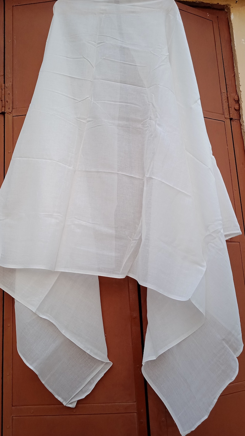 May include: A white cotton scarf draped over a brown door. The scarf is folded in half and has a smooth texture.