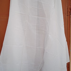 May include: A white cotton scarf, folded and hanging on a brown door.