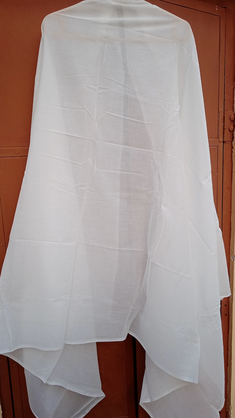 May include: A white cotton scarf, folded and hanging on a brown door.