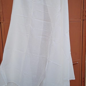 May include: A white sheer scarf hanging on a hanger against a brown wooden door.