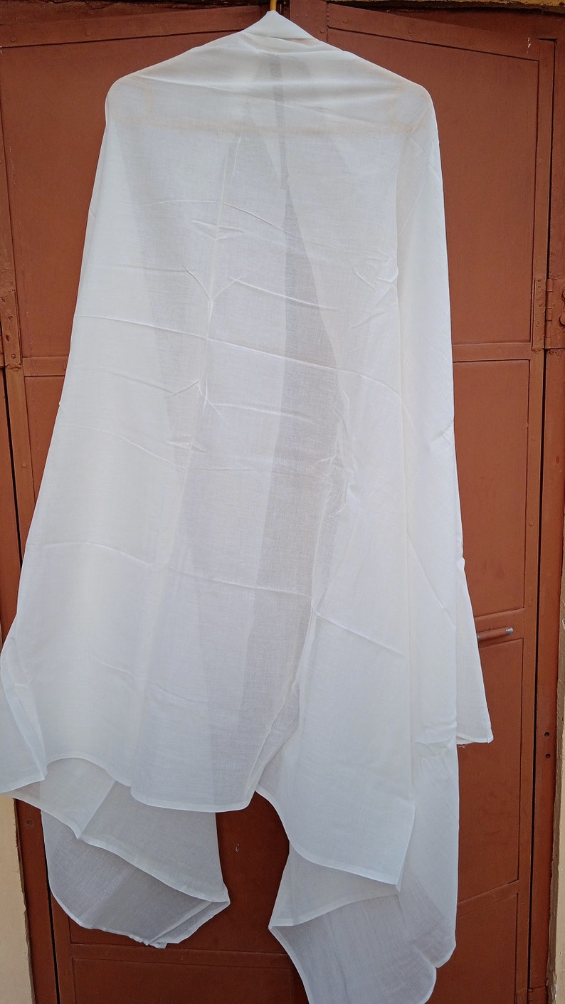 May include: A white sheer scarf hanging on a hanger against a brown wooden door.
