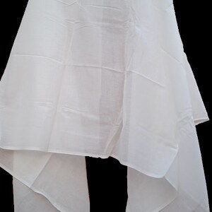 May include: A white sheer scarf with a smooth texture. The scarf is folded in half and draped over a surface.