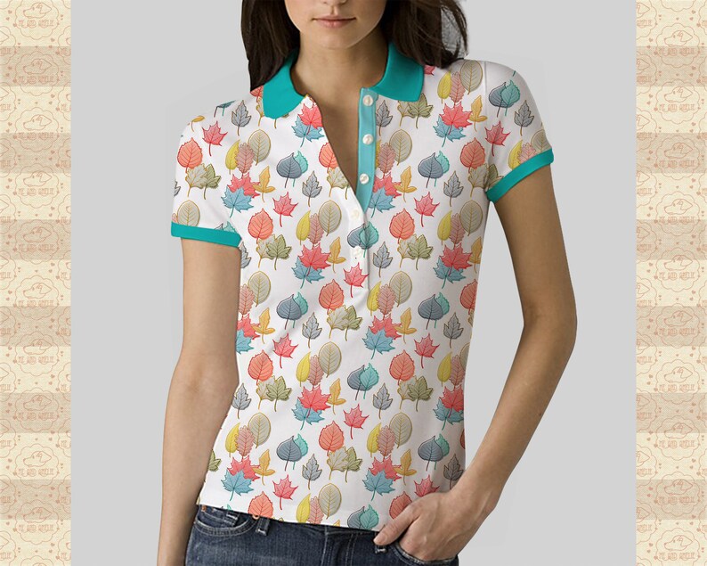 May include: A white polo shirt with a teal collar and trim. The shirt features a colourful leaf pattern.