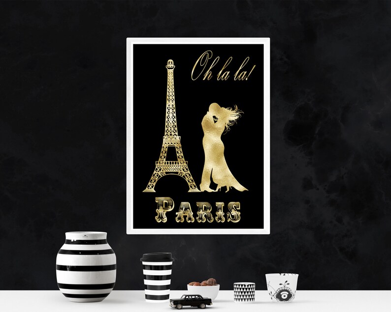 May include: A black and gold print featuring a silhouette of the Eiffel Tower and a couple kissing. The text "Oh la la!" and "PARIS" is in gold lettering.