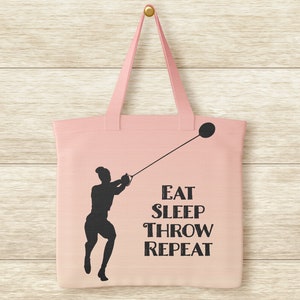 Pu&ograve; includere: Una borsa di tela rosa con la silhouette di una persona che lancia un martello. Il testo sulla borsa dice "Eat Sleep Throw Repeat."