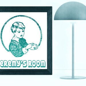 Op de afbeelding: Een turquoise ingelijst print met een zwart-witte illustratie van een jongen die een kopje vasthoudt. De tekst "Jeremy's Room" is in turquoise onder de illustratie gedrukt.