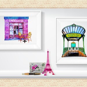 May include: Two framed watercolor paintings of Parisian scenes. The first painting shows a pink cafe with the words "Cafe des Arts" above the entrance. The second painting shows a green and yellow Parisian metro entrance with the words "METROPOLITAIN" above the entrance.