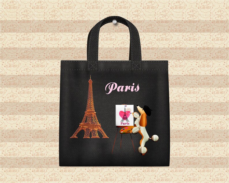 May include: Black tote bag with a white Eiffel Tower, a pink heart, and a poodle painting a picture of the Eiffel Tower. The bag has the word "Paris" written in pink letters.
